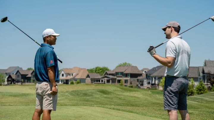 Two golfers chatting on the course with drivers over their shoulders