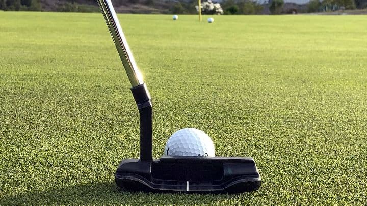 Putter lined up behind a golf ball on the practice green